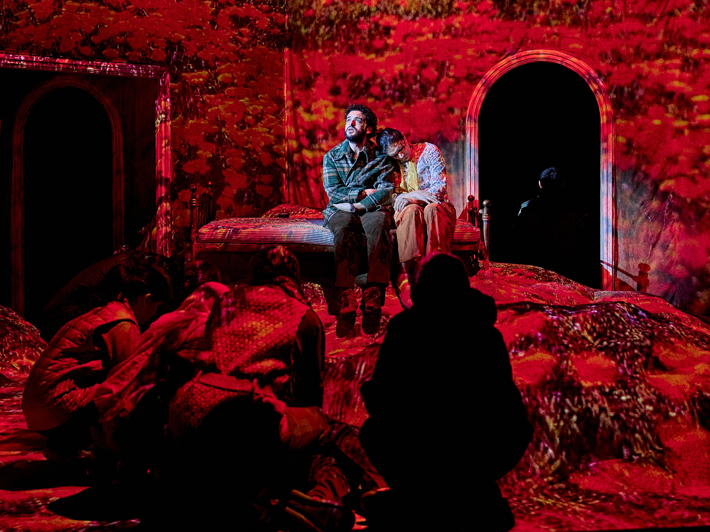 a theatre stage with two people in a white spotlight and everything else in red light