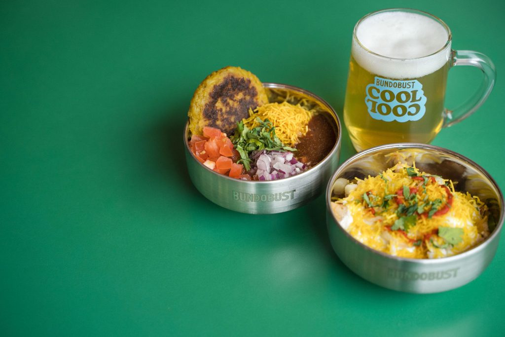 two bowls of food and a beer sitting on a table