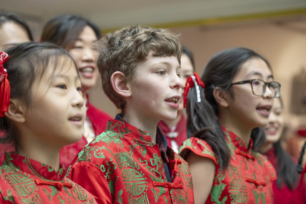 a group of children in traditional chinese tops in red, singing