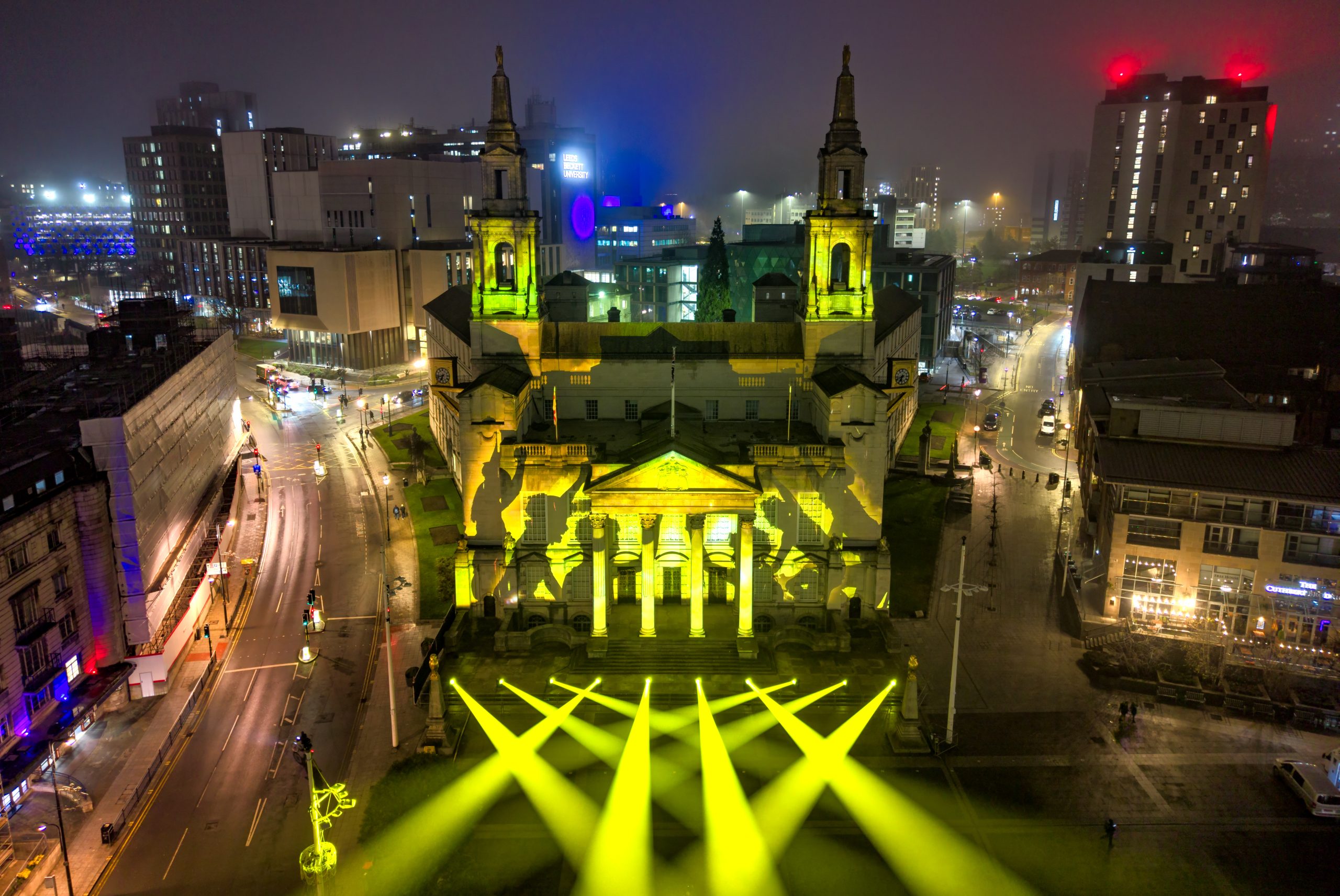 a large civic building at night time with yellow spotlights