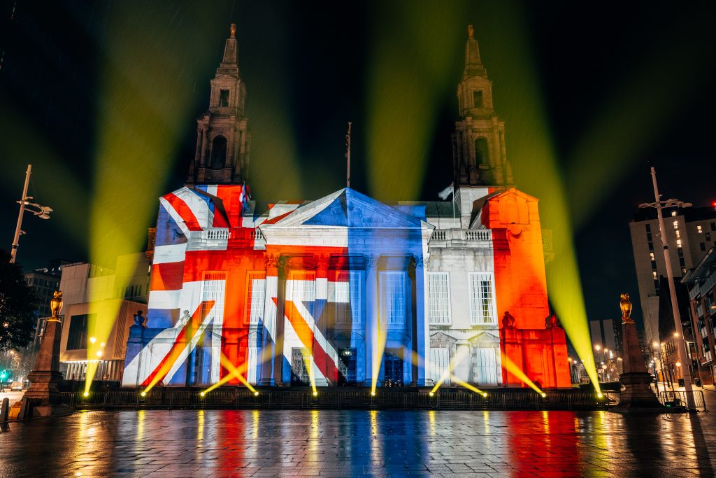 a large civic building with the union jack and french flags projected on it