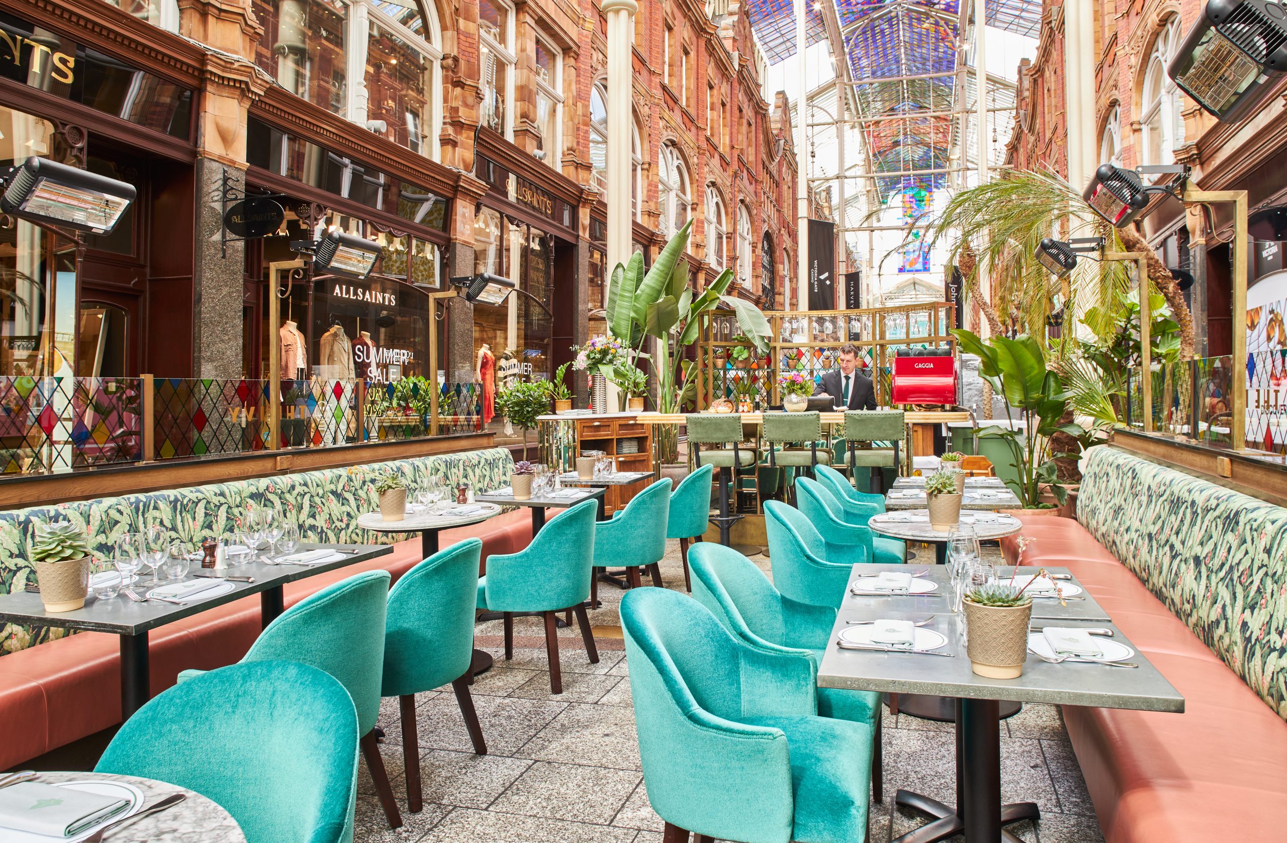 several tables and chairs lined up in an area under a glass roof in an arcade space