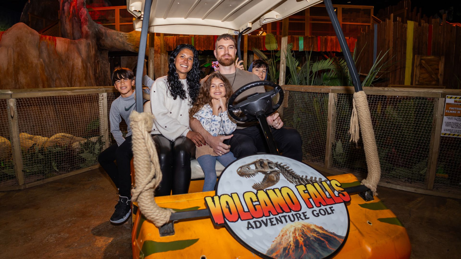 a family sat in a vehicle thats branded volcano falls adventure golf