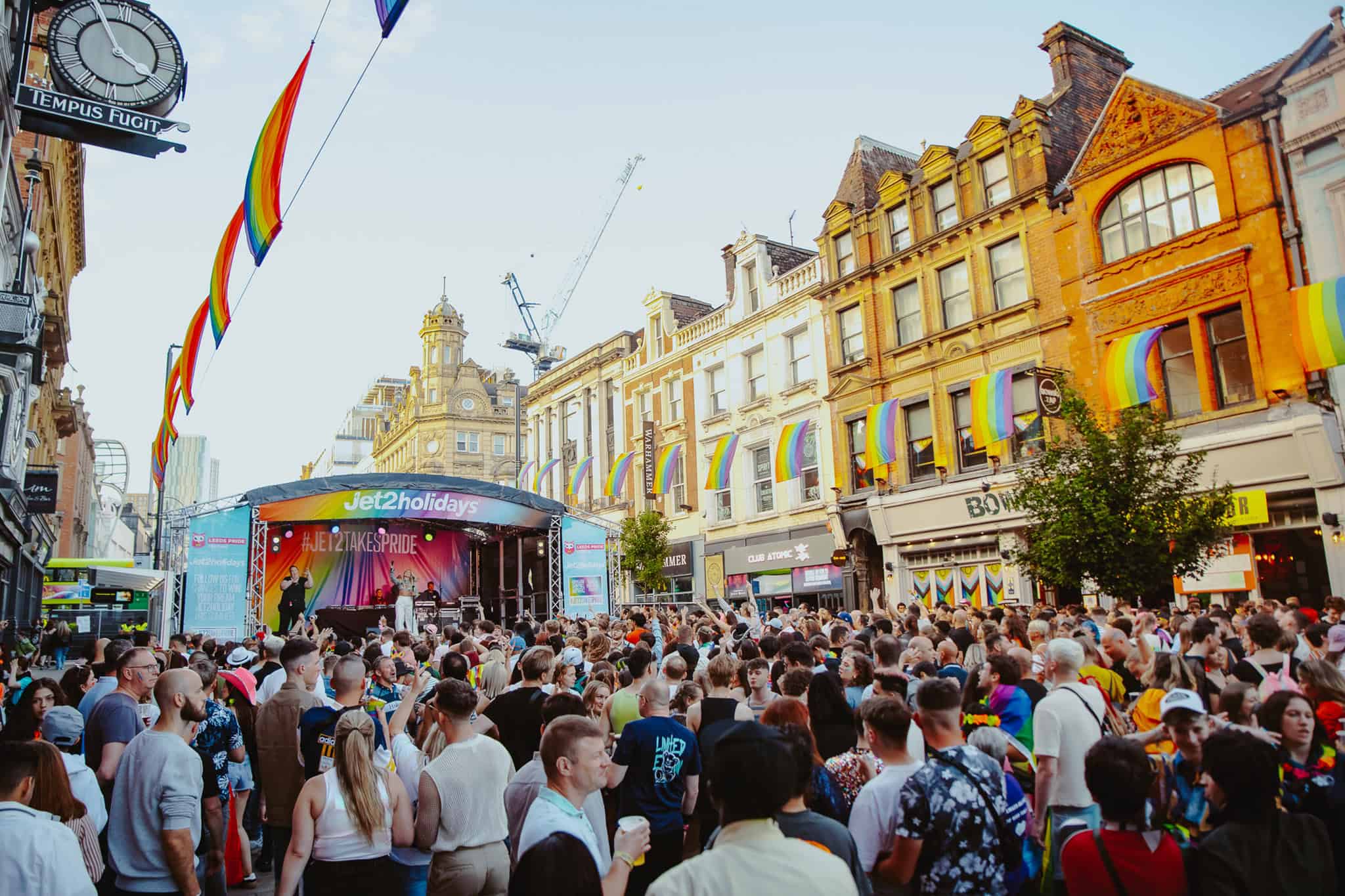a large pride parade, full of rainbows outside and a small stage at the end of the street