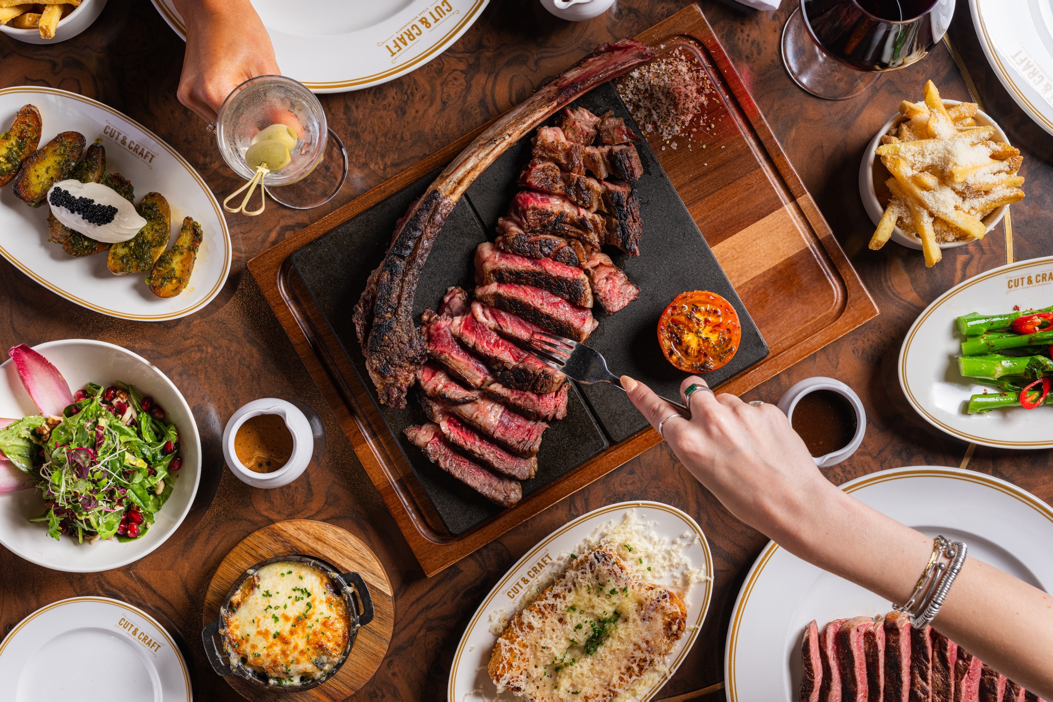 a top view of t able with food laid out including a large tomahawk steak and some drinks