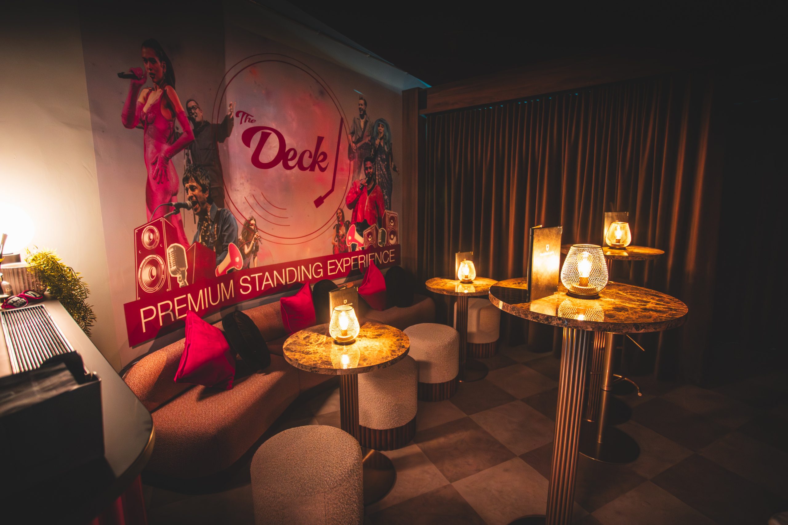bar tables with chairs, candles on the tables and a wall saying 'the deck'
