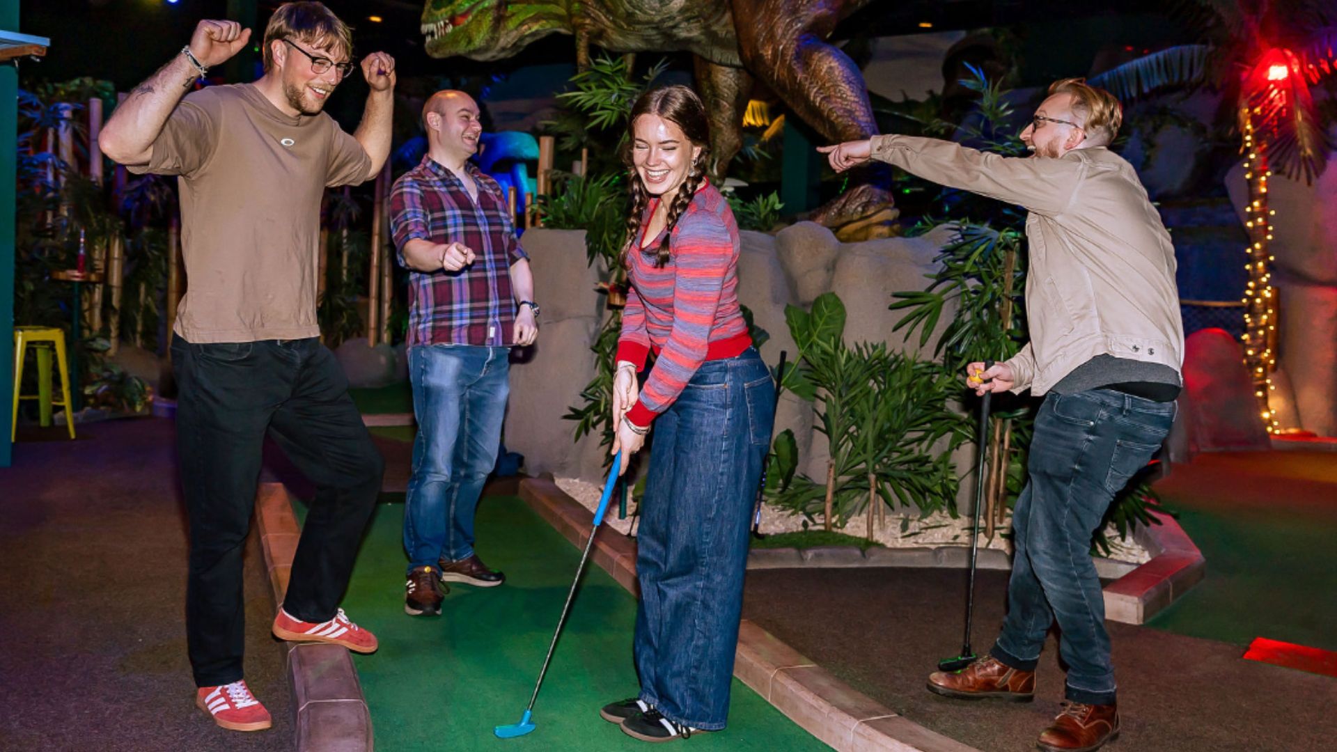 a group of people playing mini golf with green foliage around the scenery