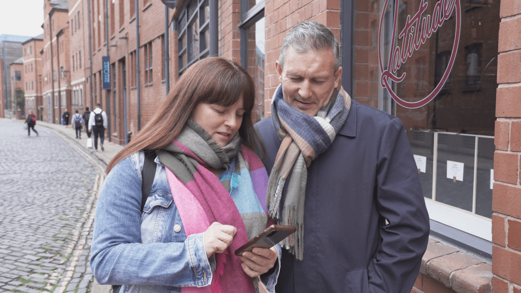 two people looking at a phone on a cobbled street