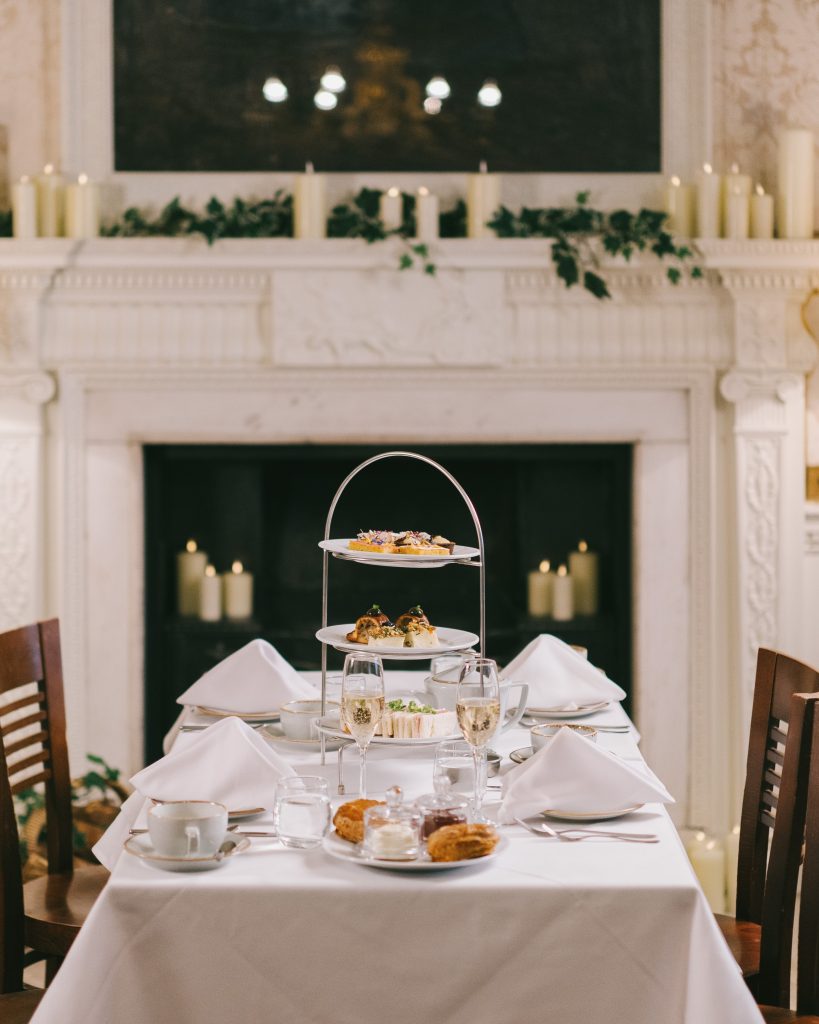 a table in front of a fireplace laid out with a stacked afternoon tea