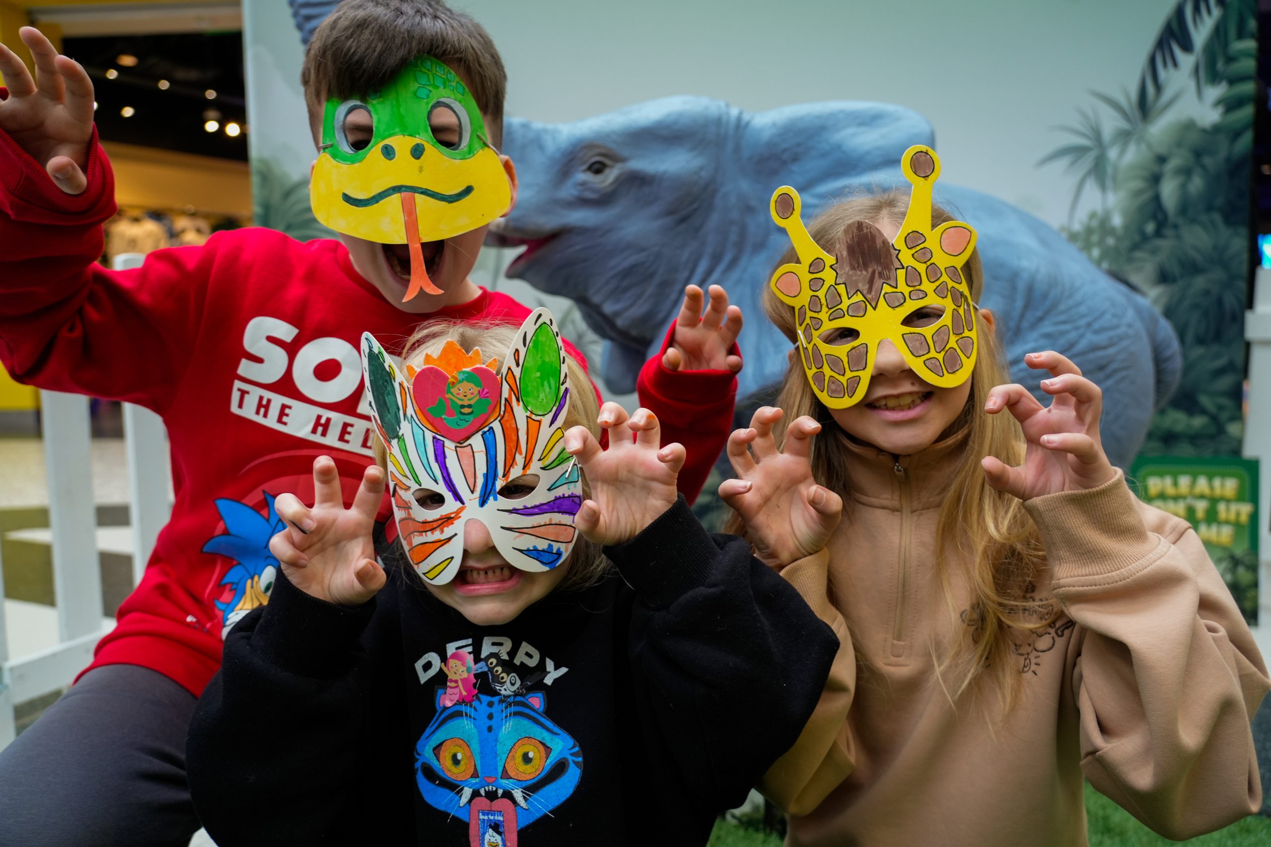 a group of children with masks on resembling a snake, a giraffe and a zebra growling at the camera