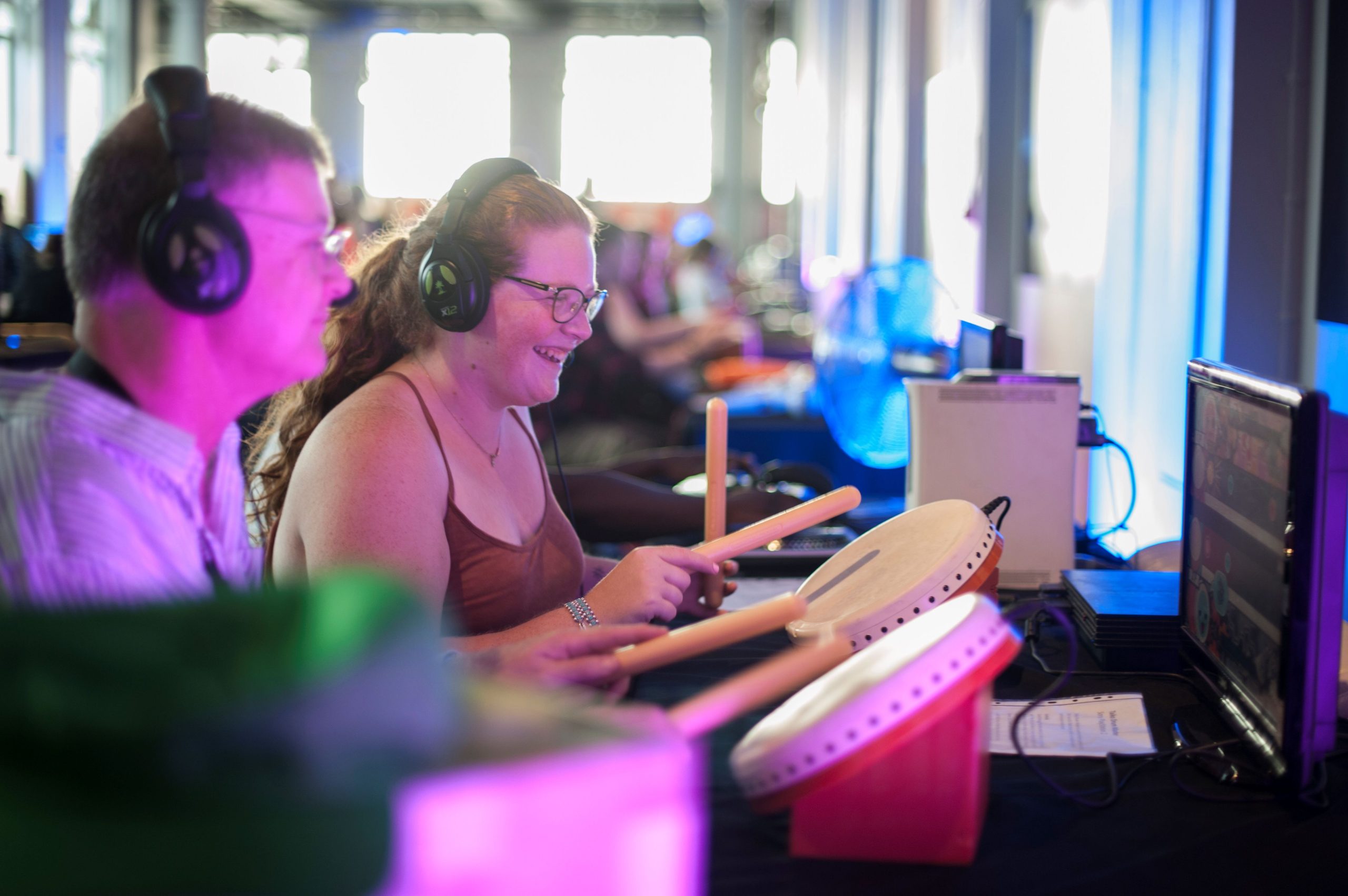 people sat at a variety of gaming consoles and arcade machines