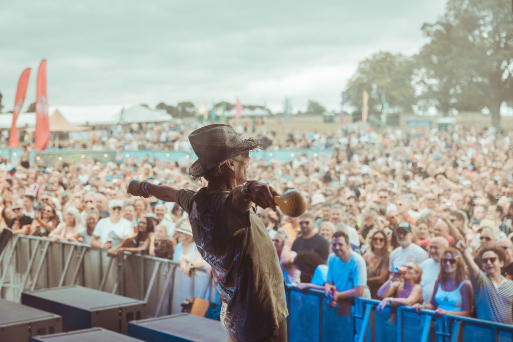 a performer on a large outdoor stage to a large crowd of people