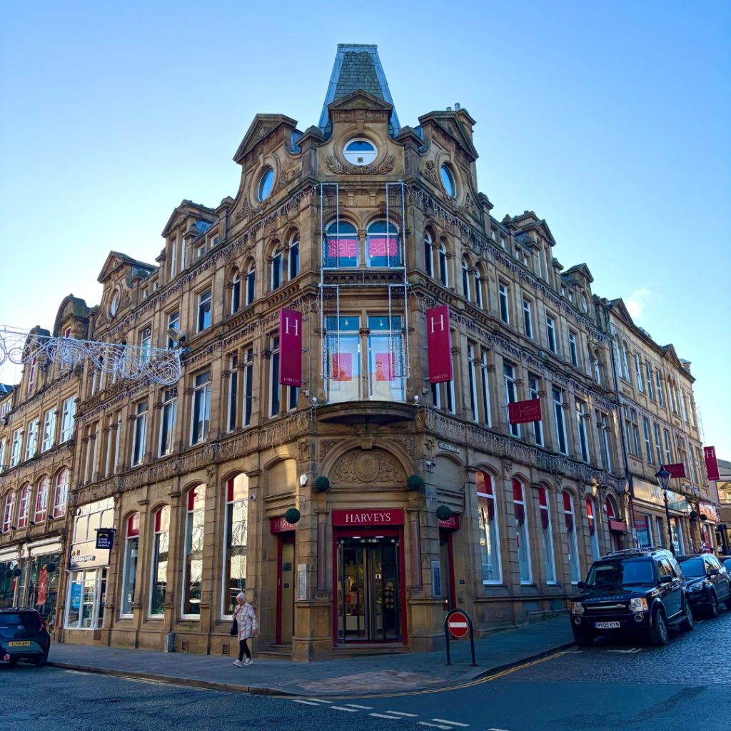 a large old four floor victorian building with signs posting it as harveys and retail shop windows on the ground level