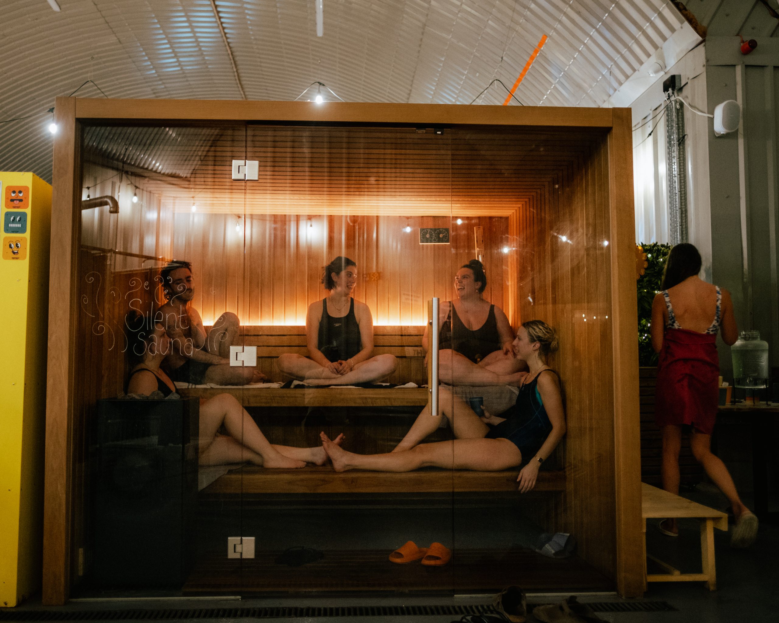 a small group of people inside a sauna room in swimming costumes