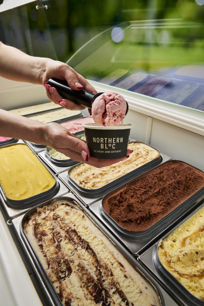 a display of ice cream with a hand scooping some into a tub