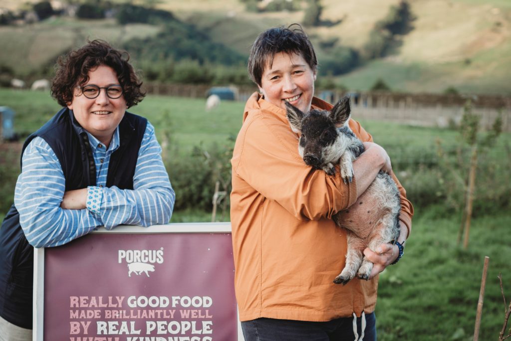 two people in a field holding a pig