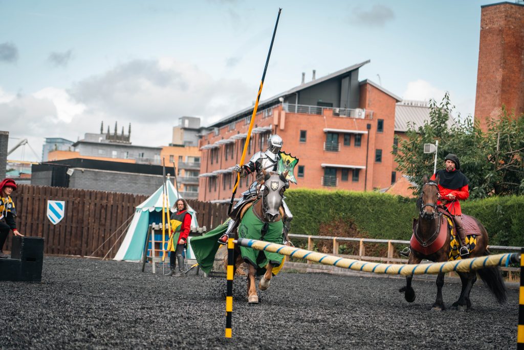 a person in armour and holding a lance jousting on horseback