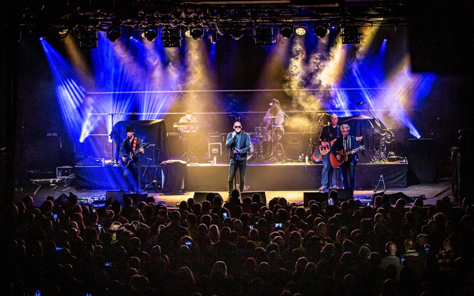 a musical band on a stage in front of a large crowd