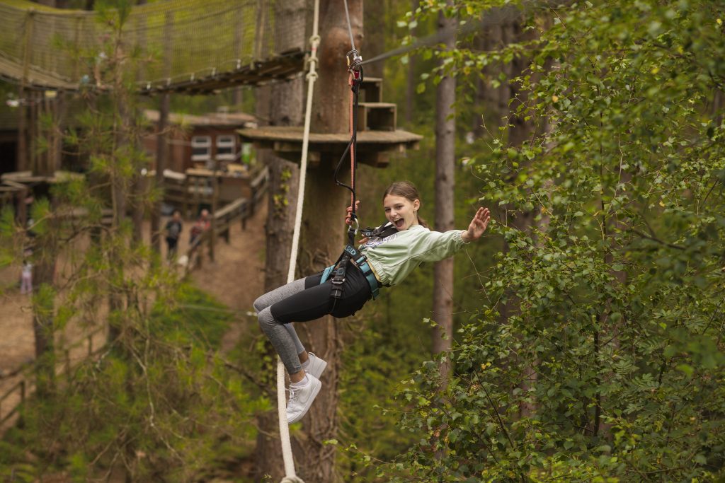 a girl on a high zipwire through the trees 