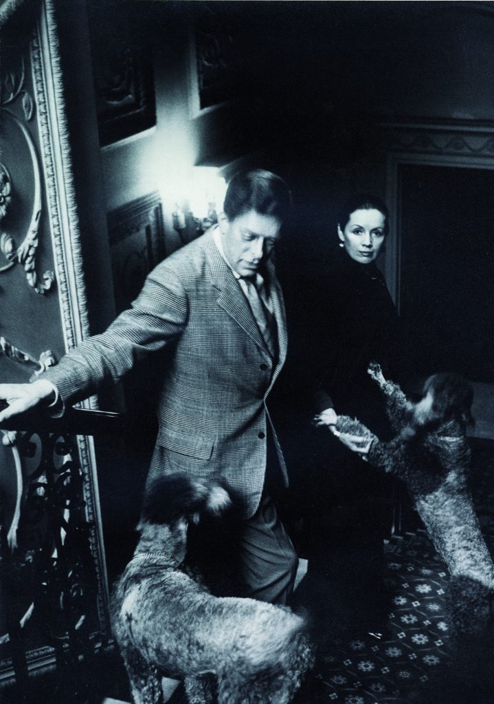 a black and white photograph of a couple on a staircase with two dogs jumping up on them