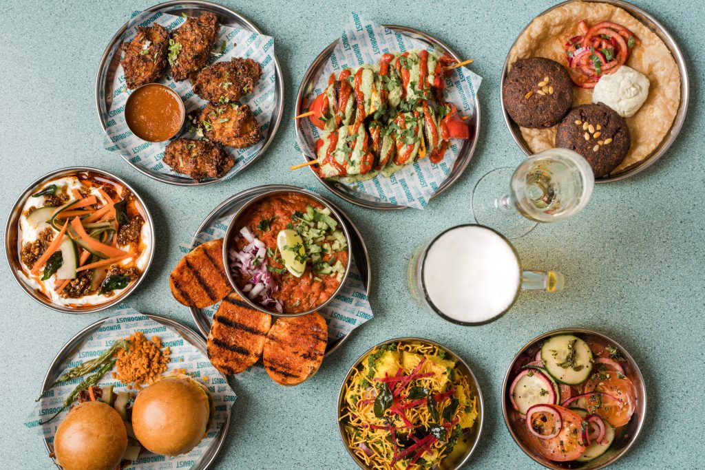 a top down view of a table filled with plates and bowls of food like burgers and some drinks