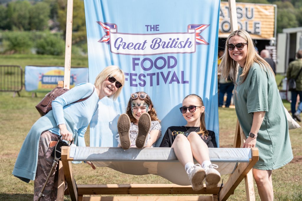 two children sat in a giant deck chair whilst they and two adults pose for the camera
