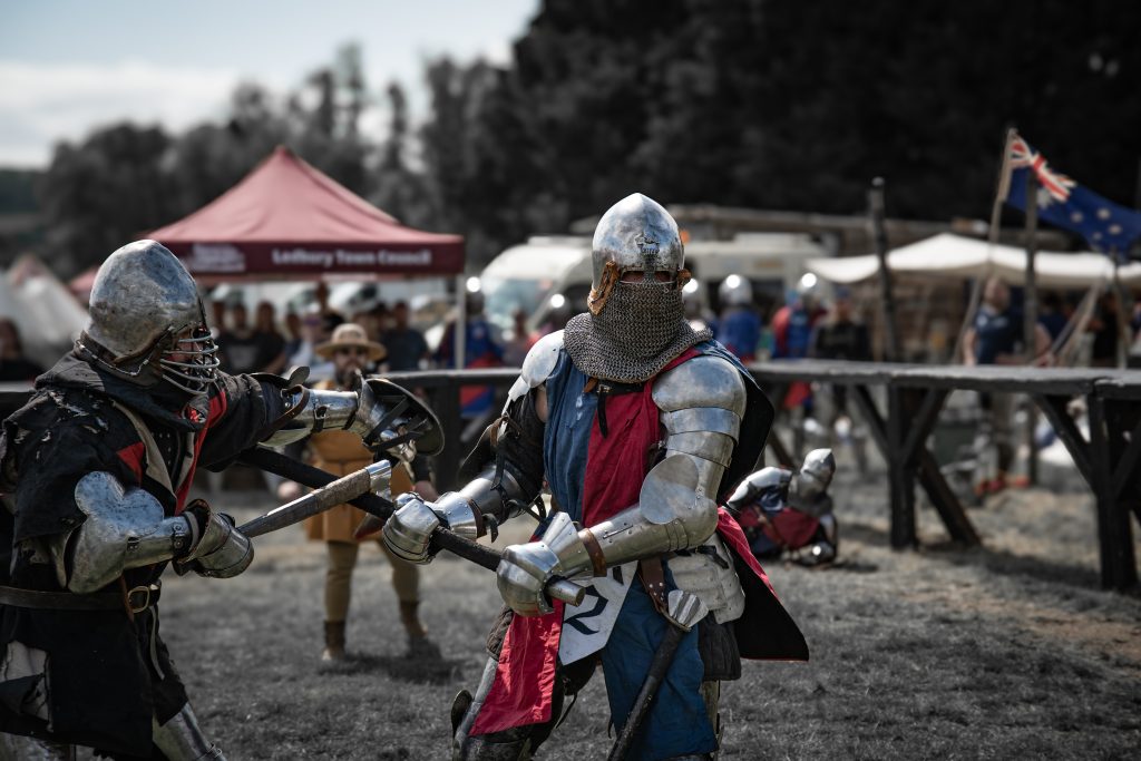 a group of people in a ring wearing armour and wielding swords and axes 