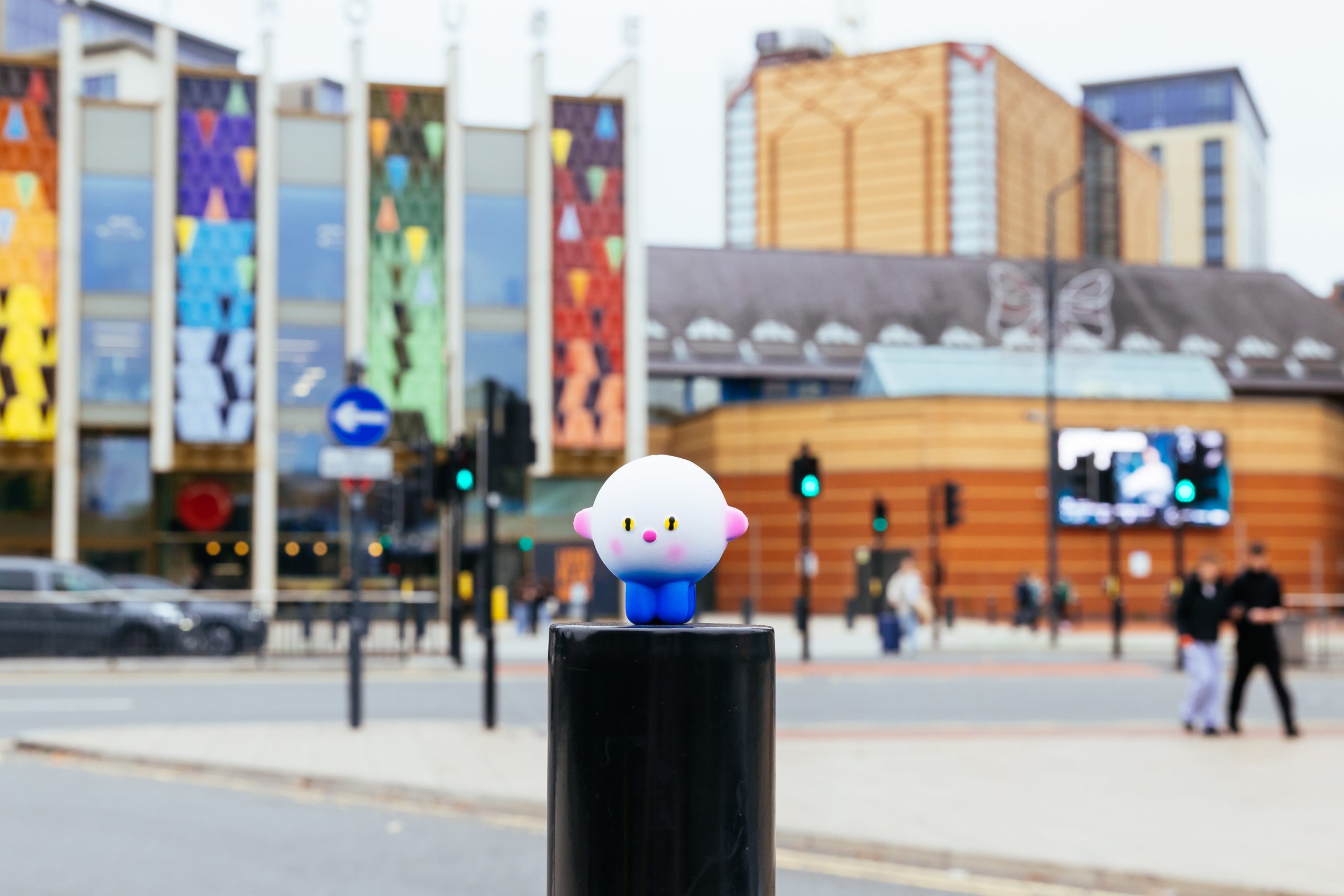 a model of the Leeds International Festival of Ideas logo, outside in front of a busy road and a large colourful building