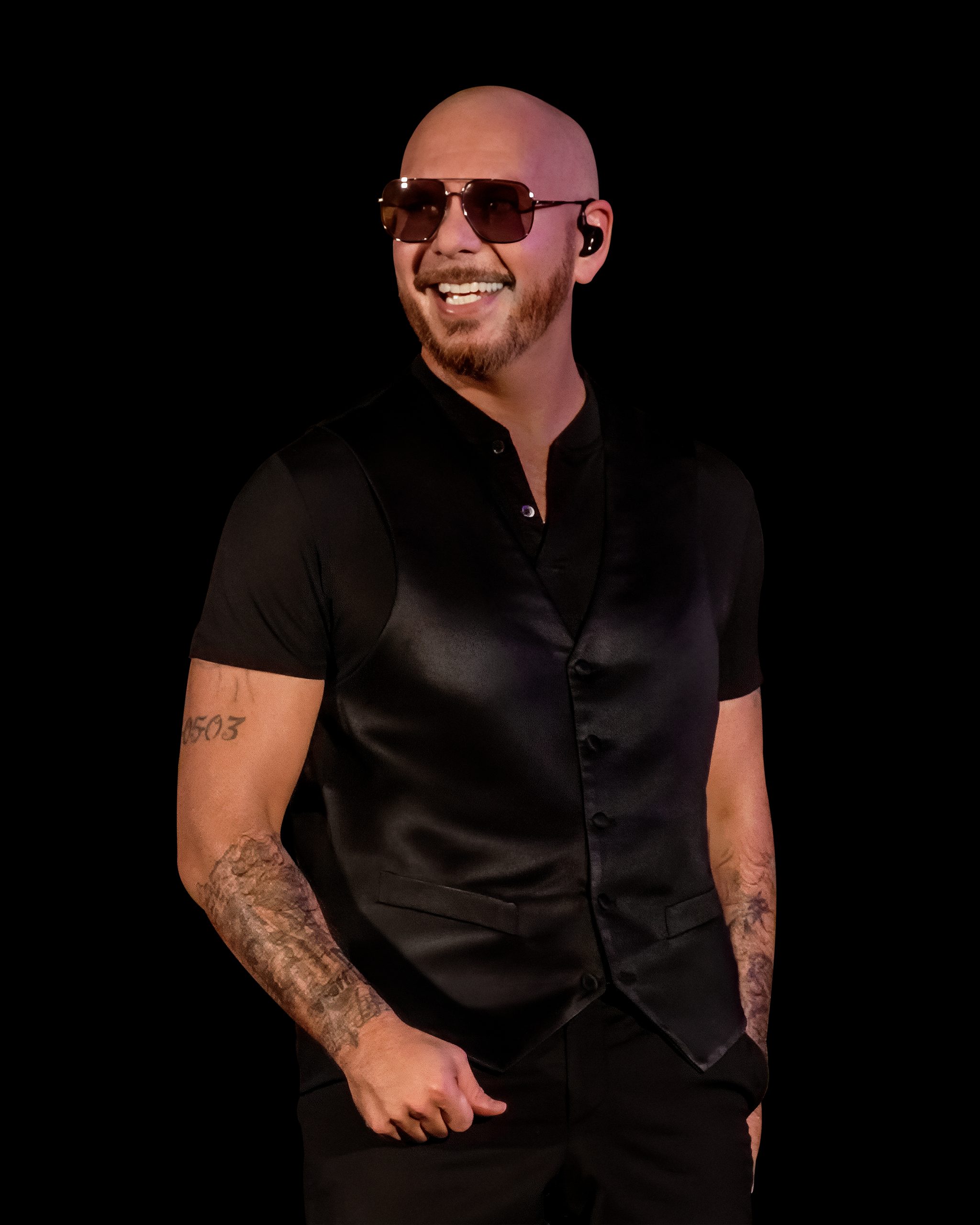 a bald man with a black shirt and dark sunglasses on smiling