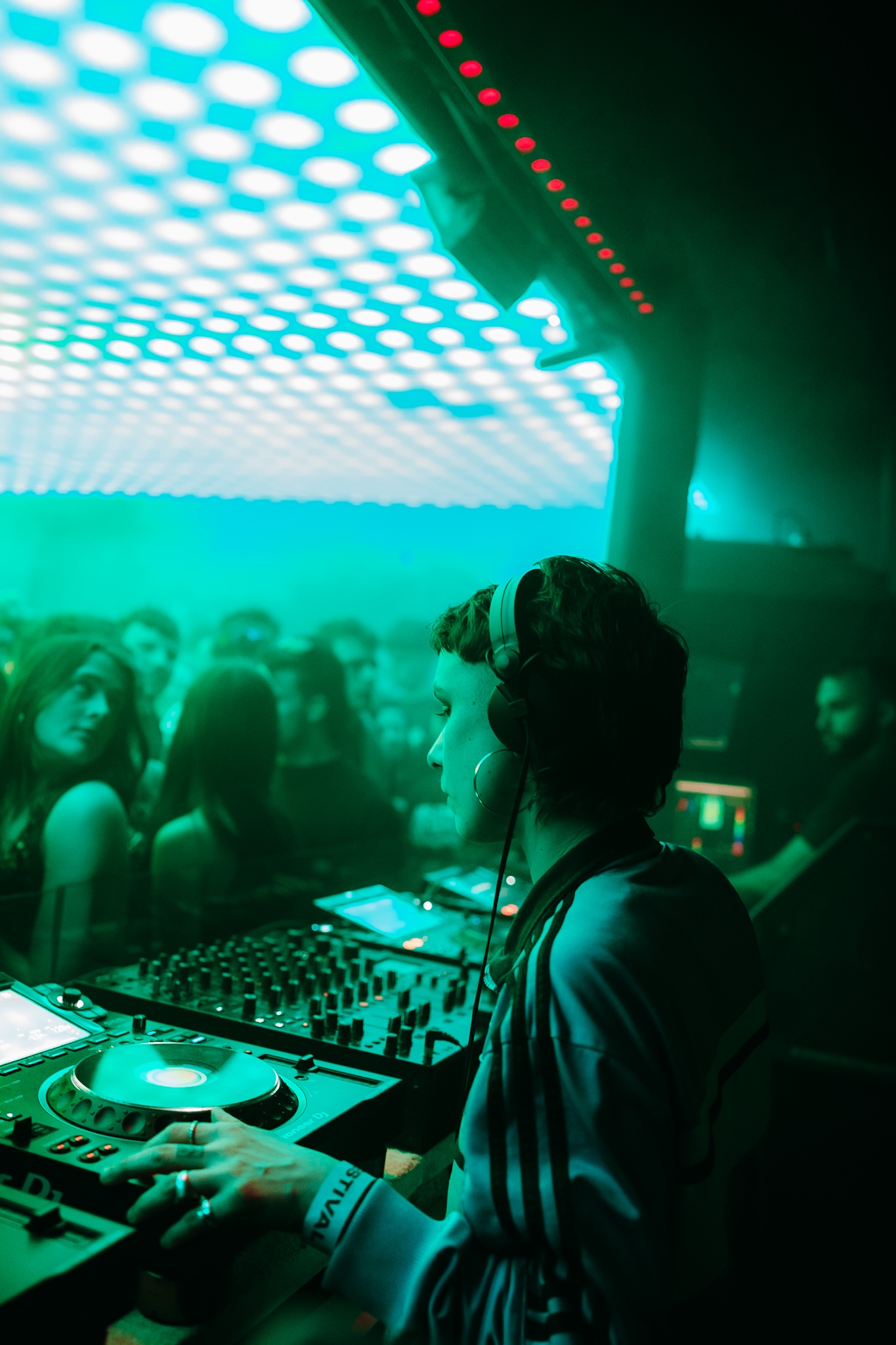 a person at a dj stand with a crowd dancing