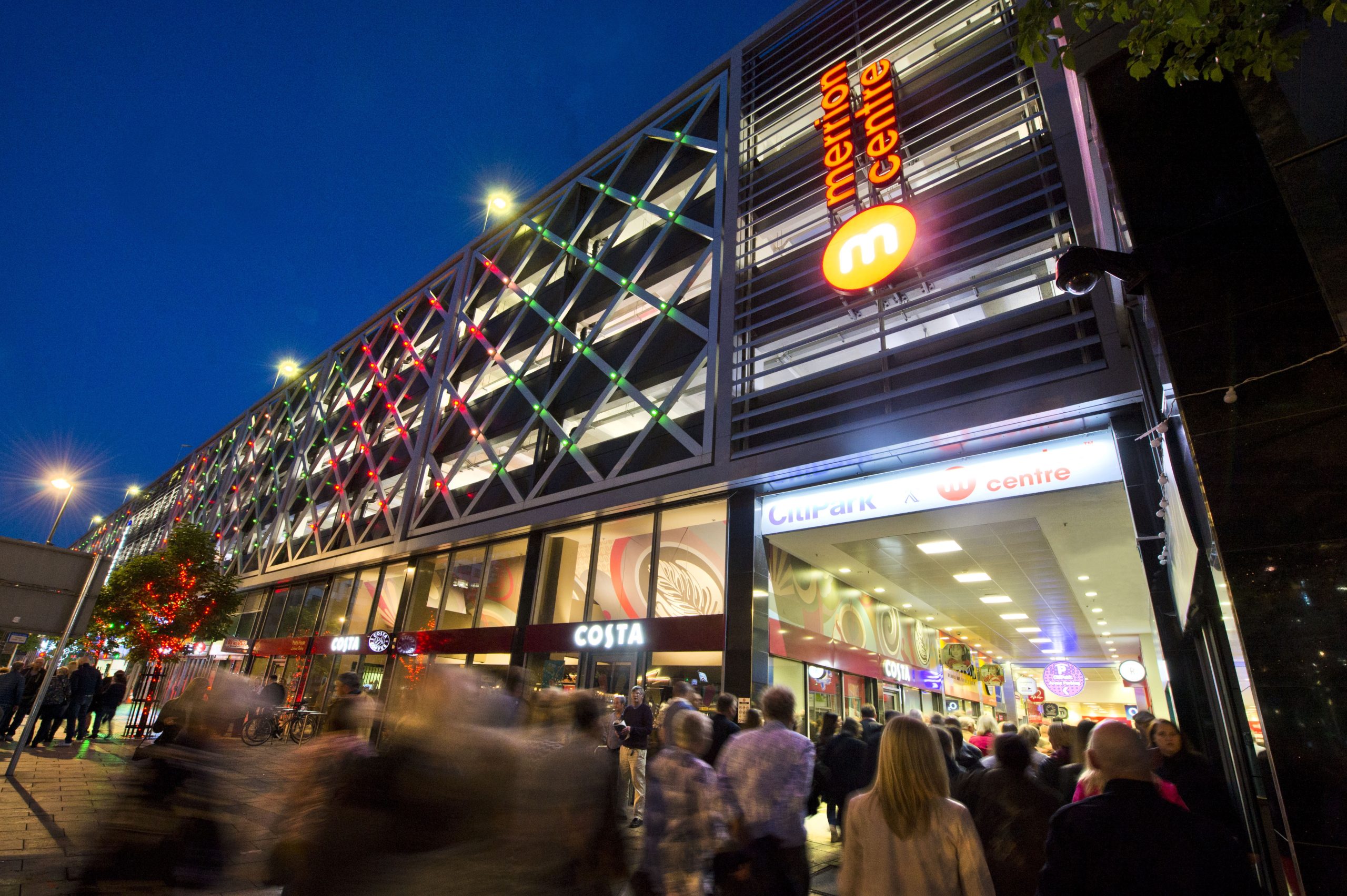 a shopping centre at night time with people walking through