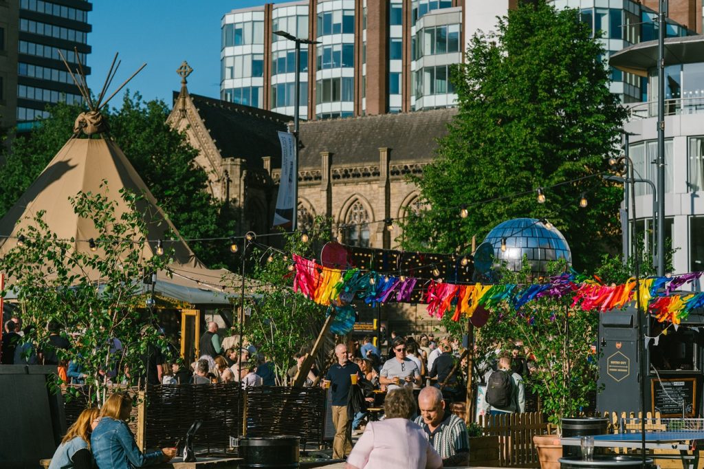 an outdoor bar with colourful flags and people drinking