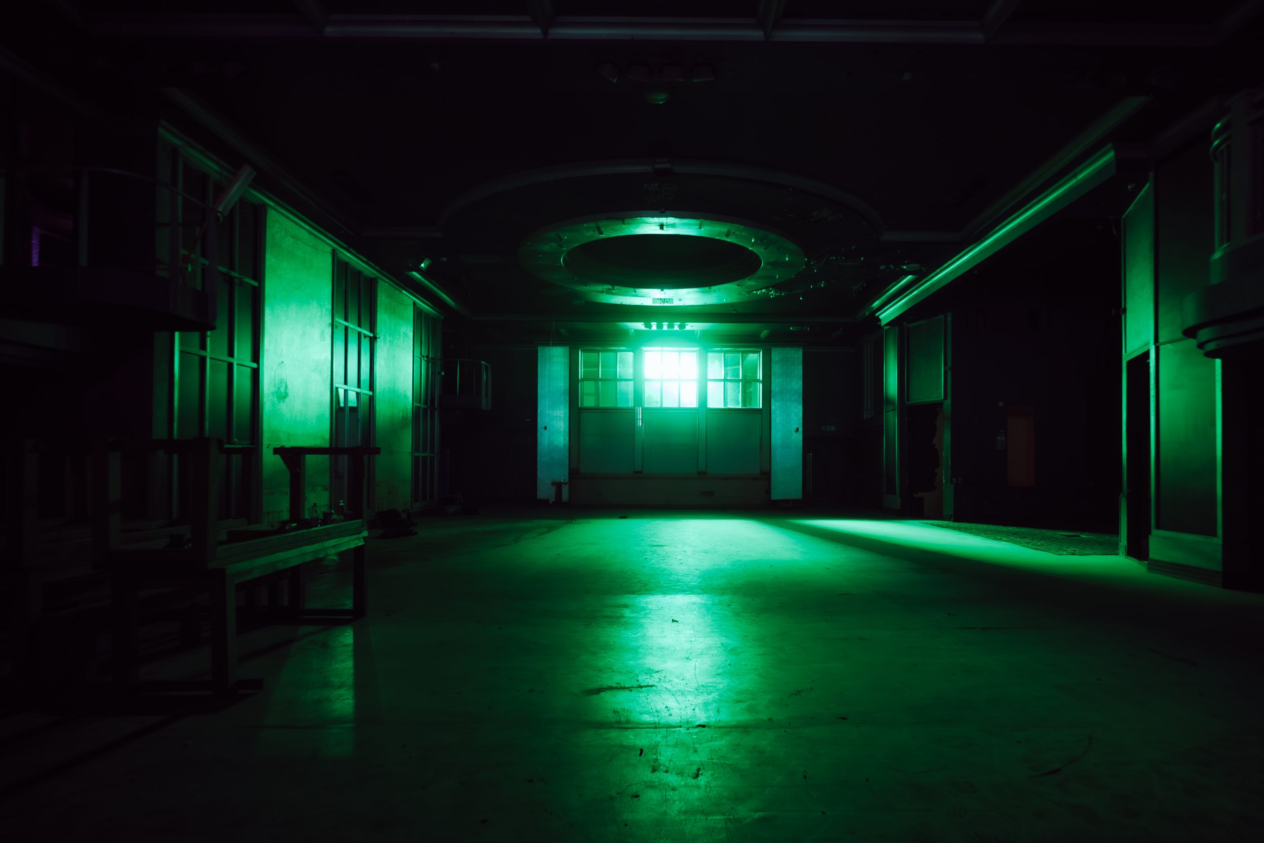 a dark room with a door on side with windows and a green light shining through