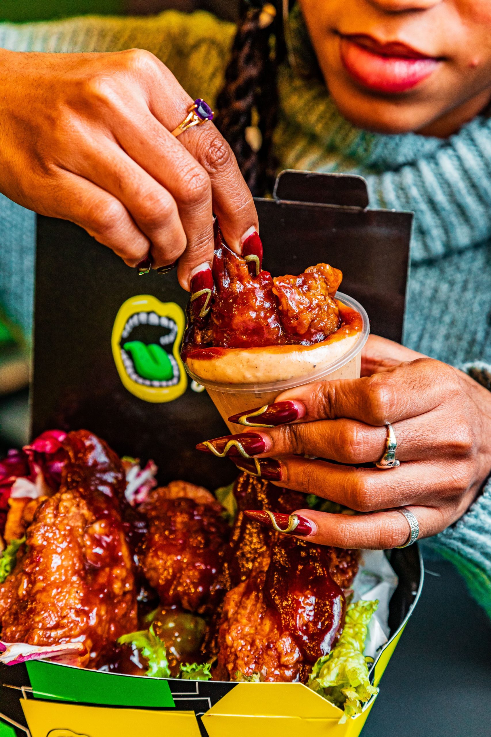 a person dipping a chicken wing into a red dip