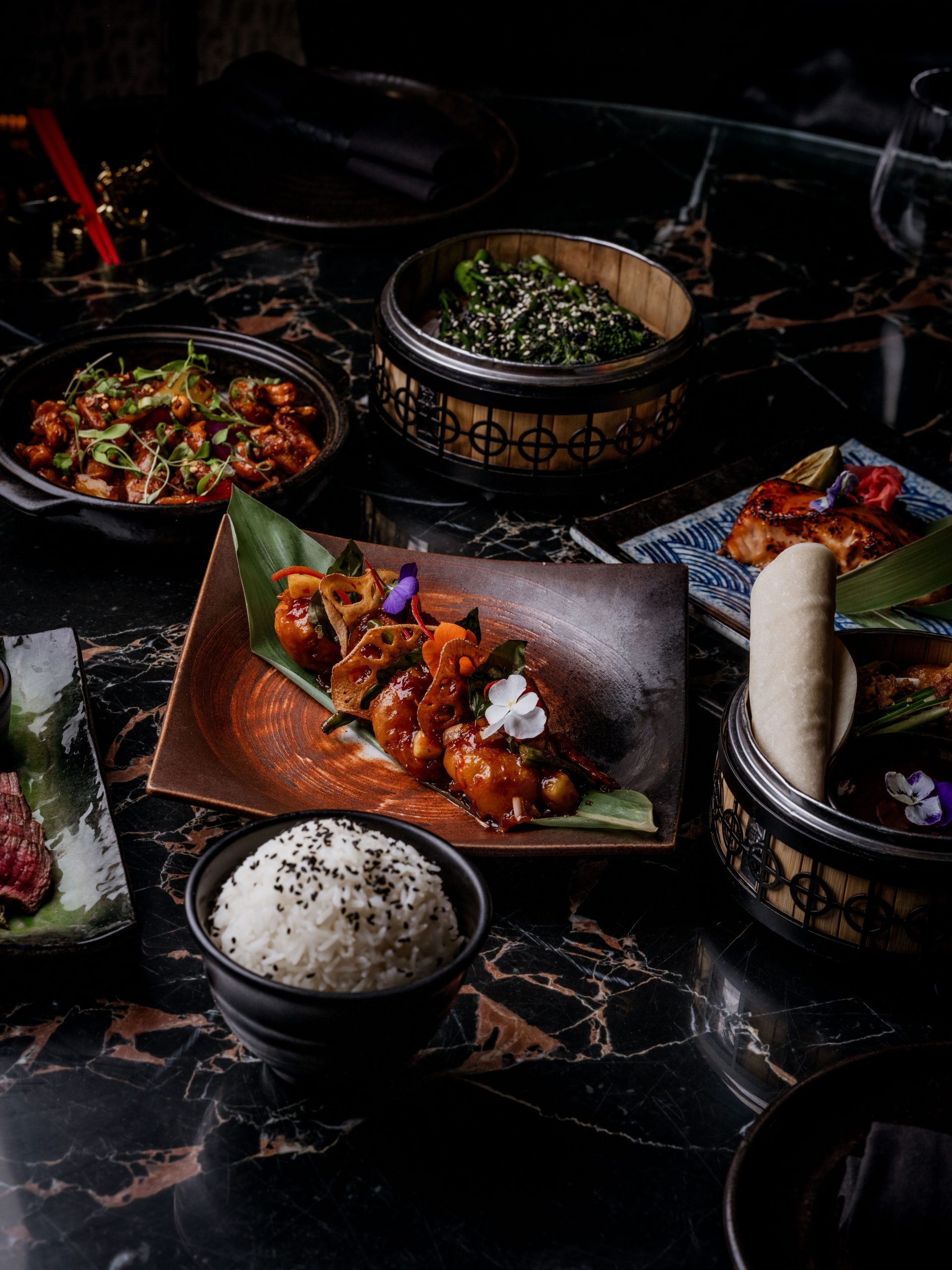 a photograph of a table of lots of different food dishes in low lighting