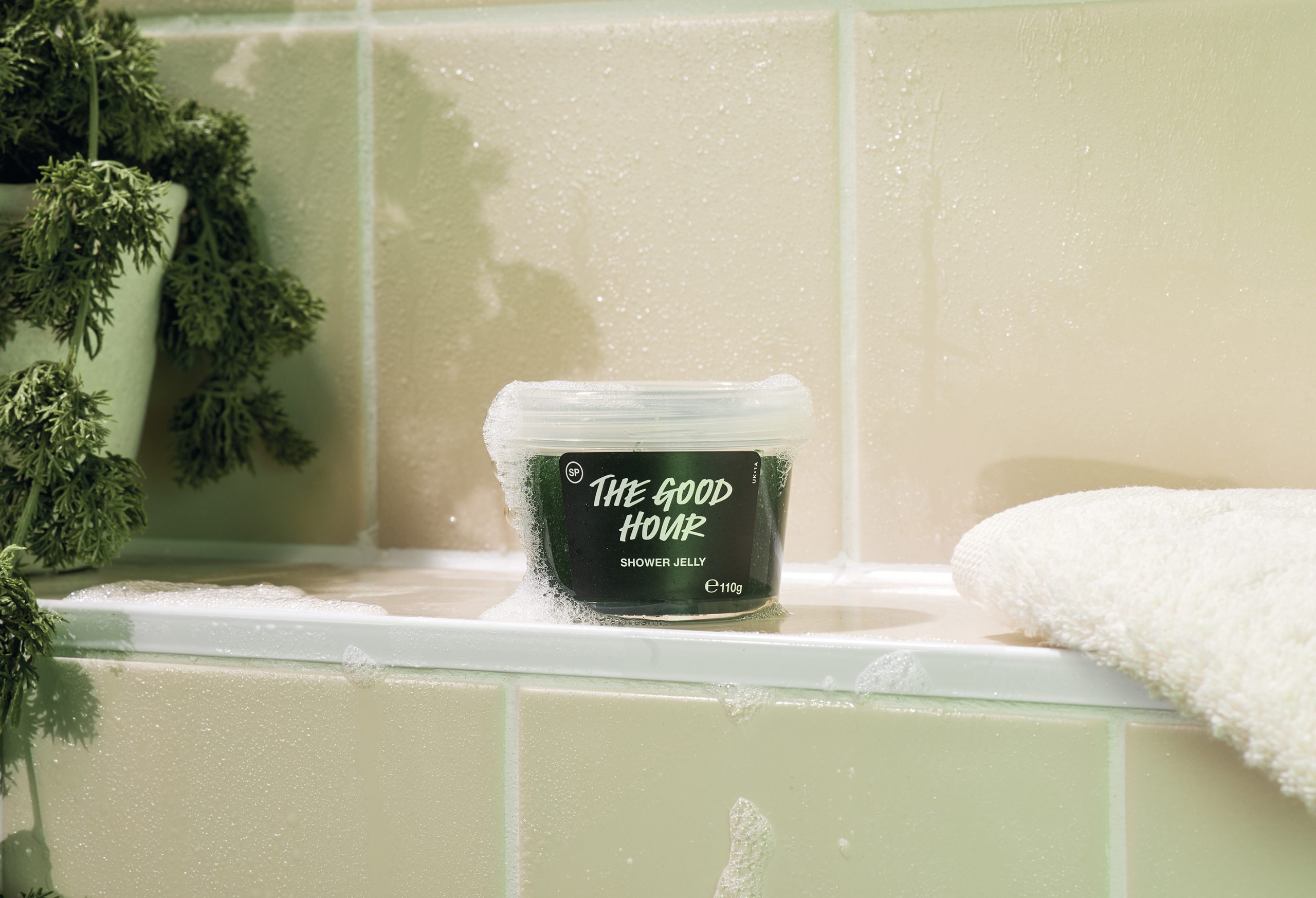 a tiled bathtub, a clear plastic tub with a green substance inside and a label saying the good hour
