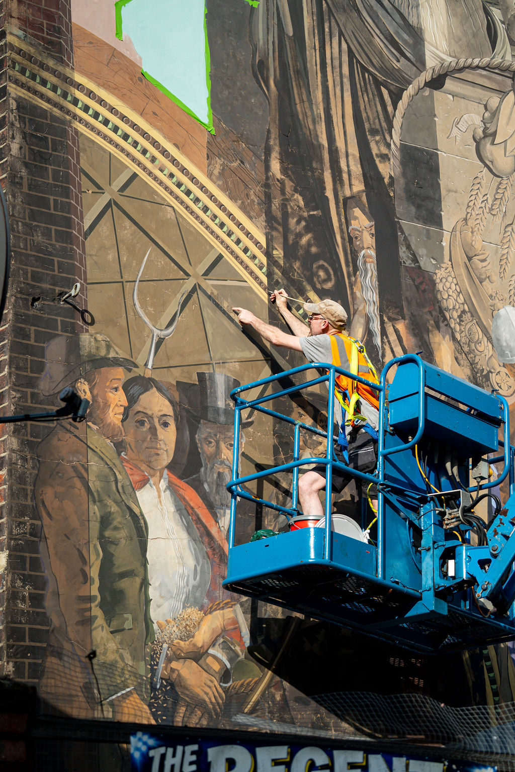 a person in a crane painting a wall mural