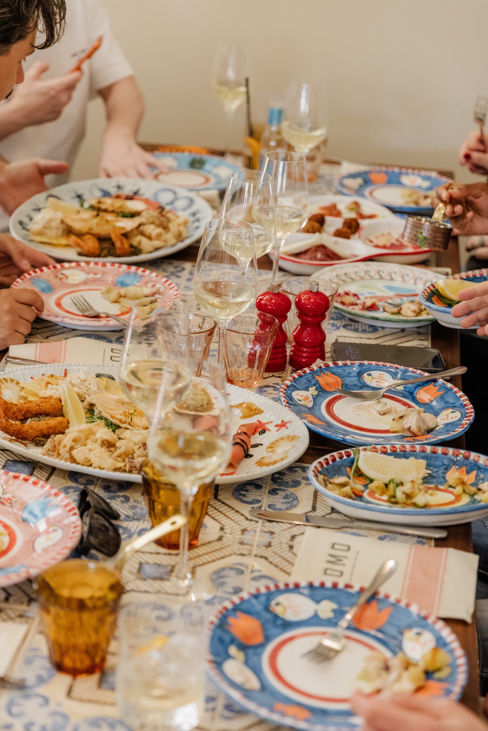a table with colourful plates filled with food, and cups of drinks