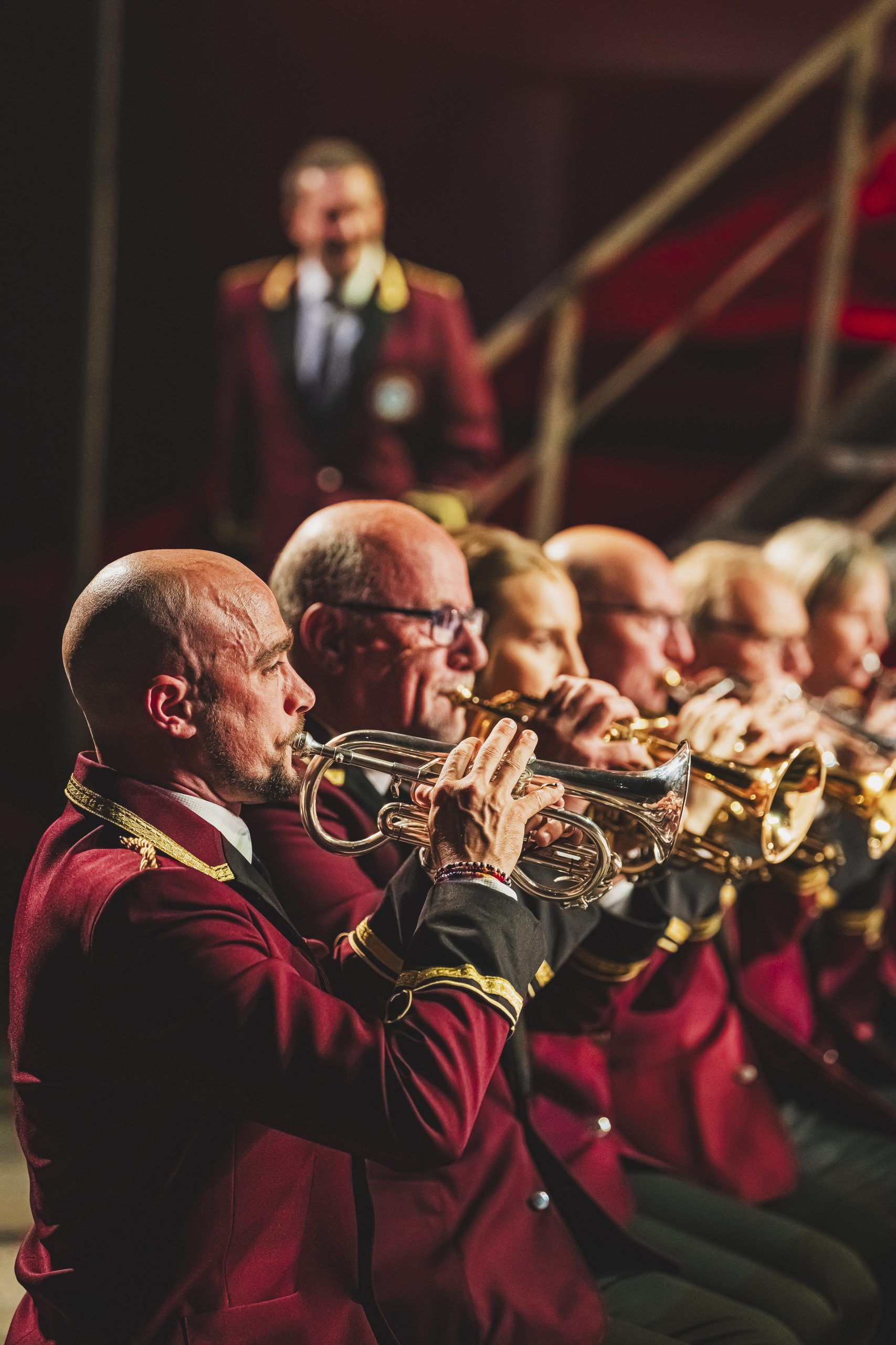 several people in a row in matching red jackets playing brass instruments