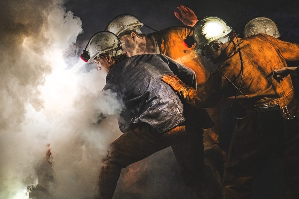 a group of miners working with smoke billowing around them