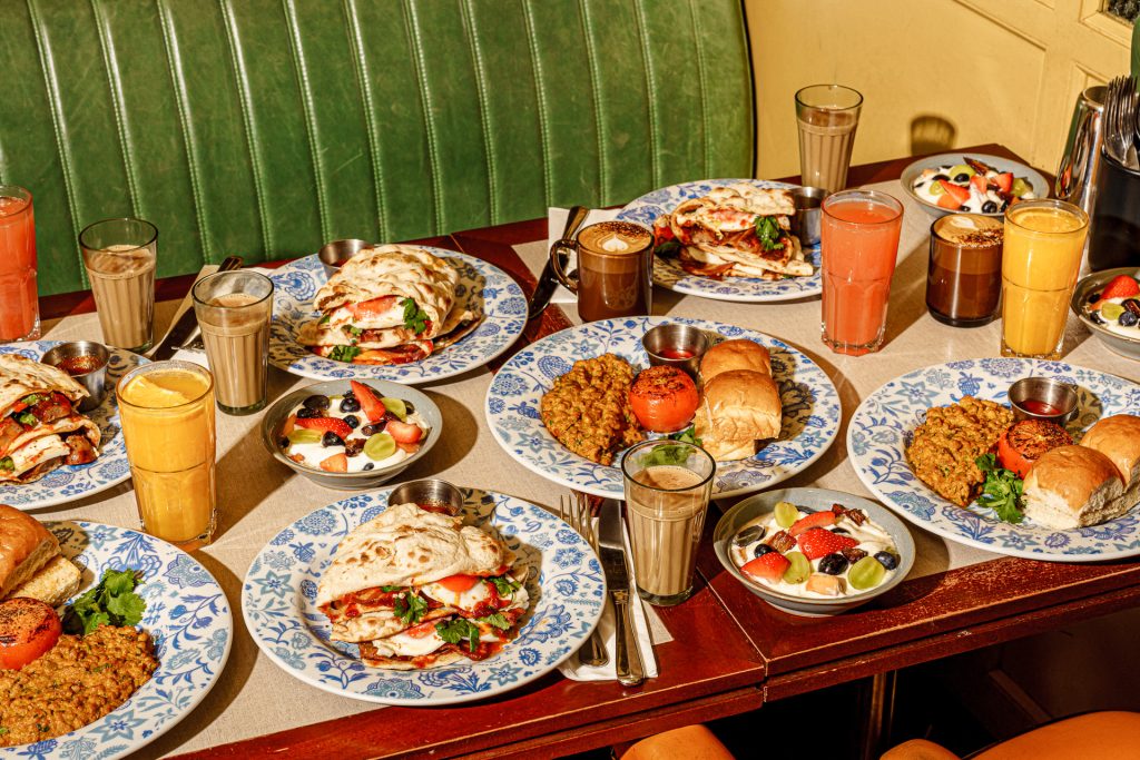 a table filled with plates, bowls and trays of food including currys and rolls