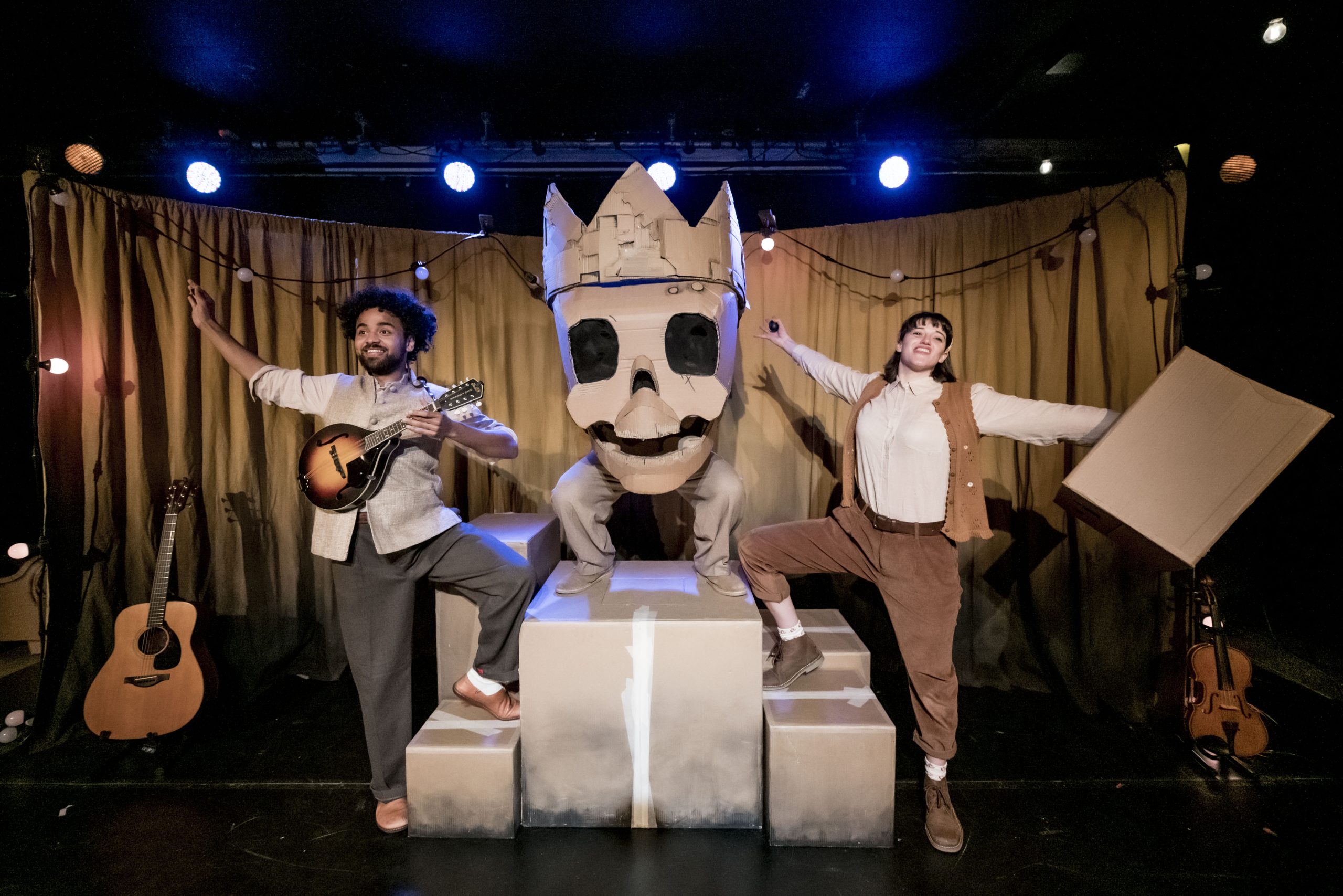 two people on a stage posing with a large setpiece of a skull with a crown on it