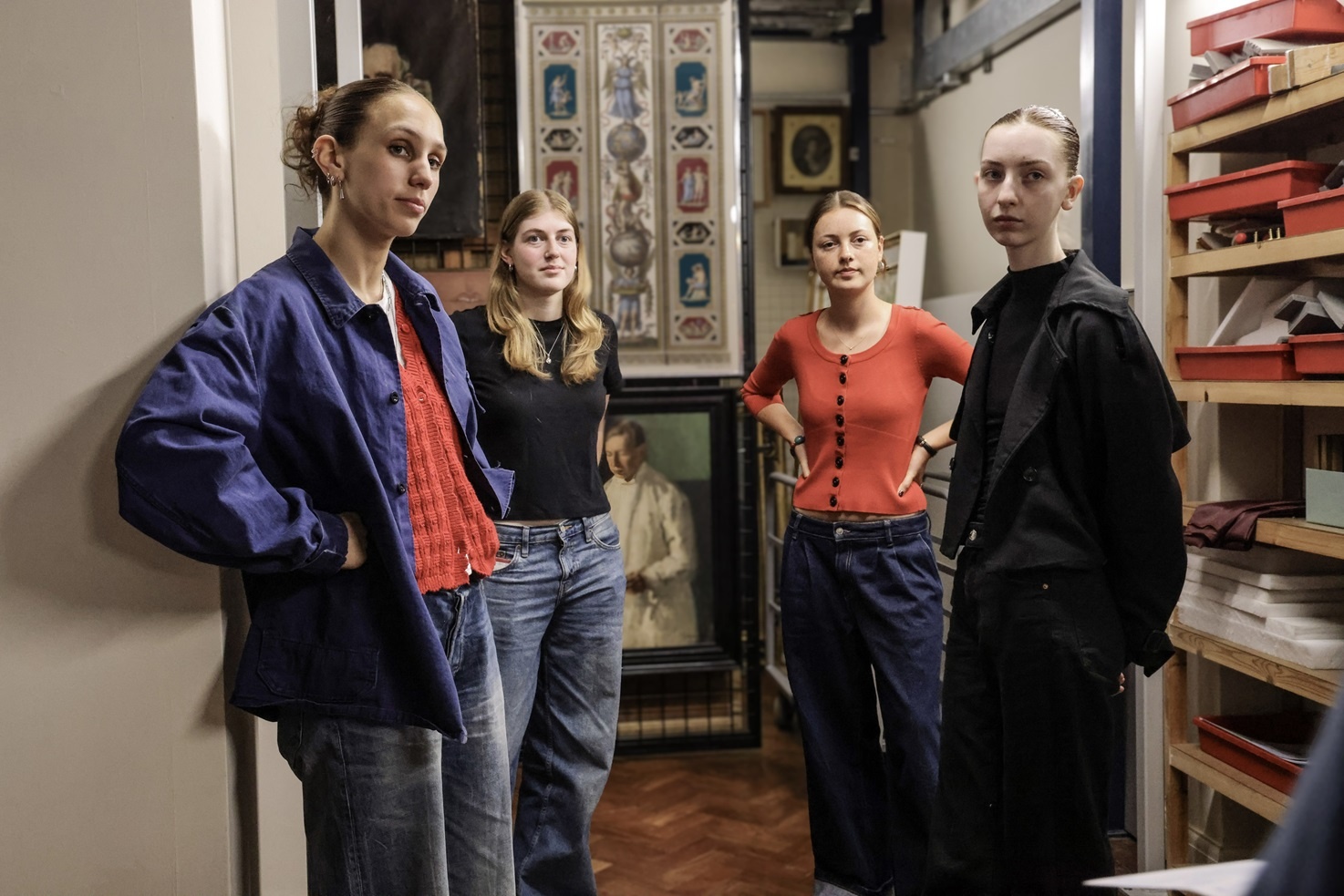 four people stood together in a room with paintings on the wall behind them