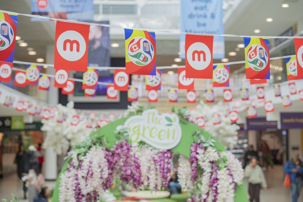 the inside of a shopping mall decorated with flags strung along with footballs on them