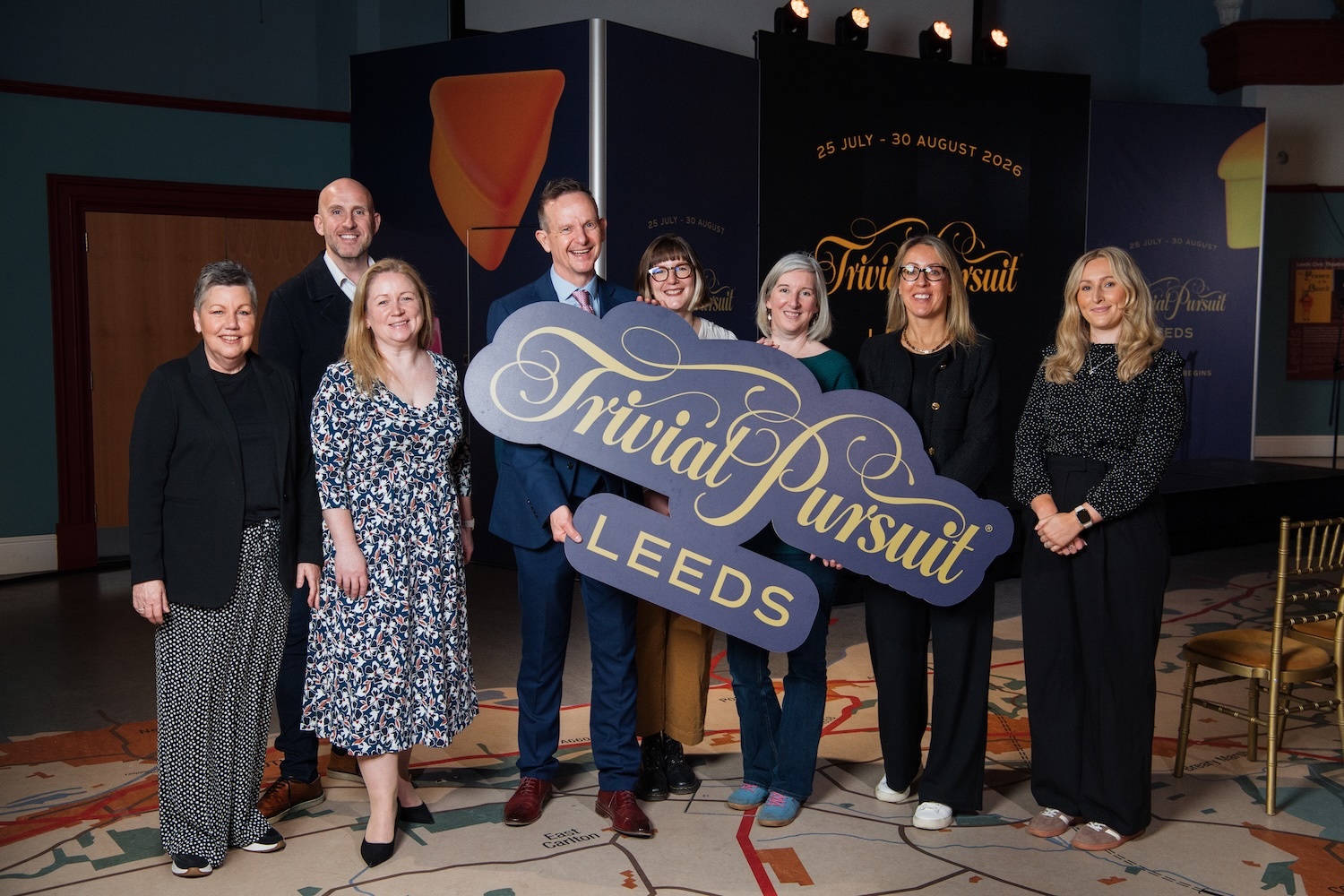 several people posing and holding a sign saying trivial pursuit leeds