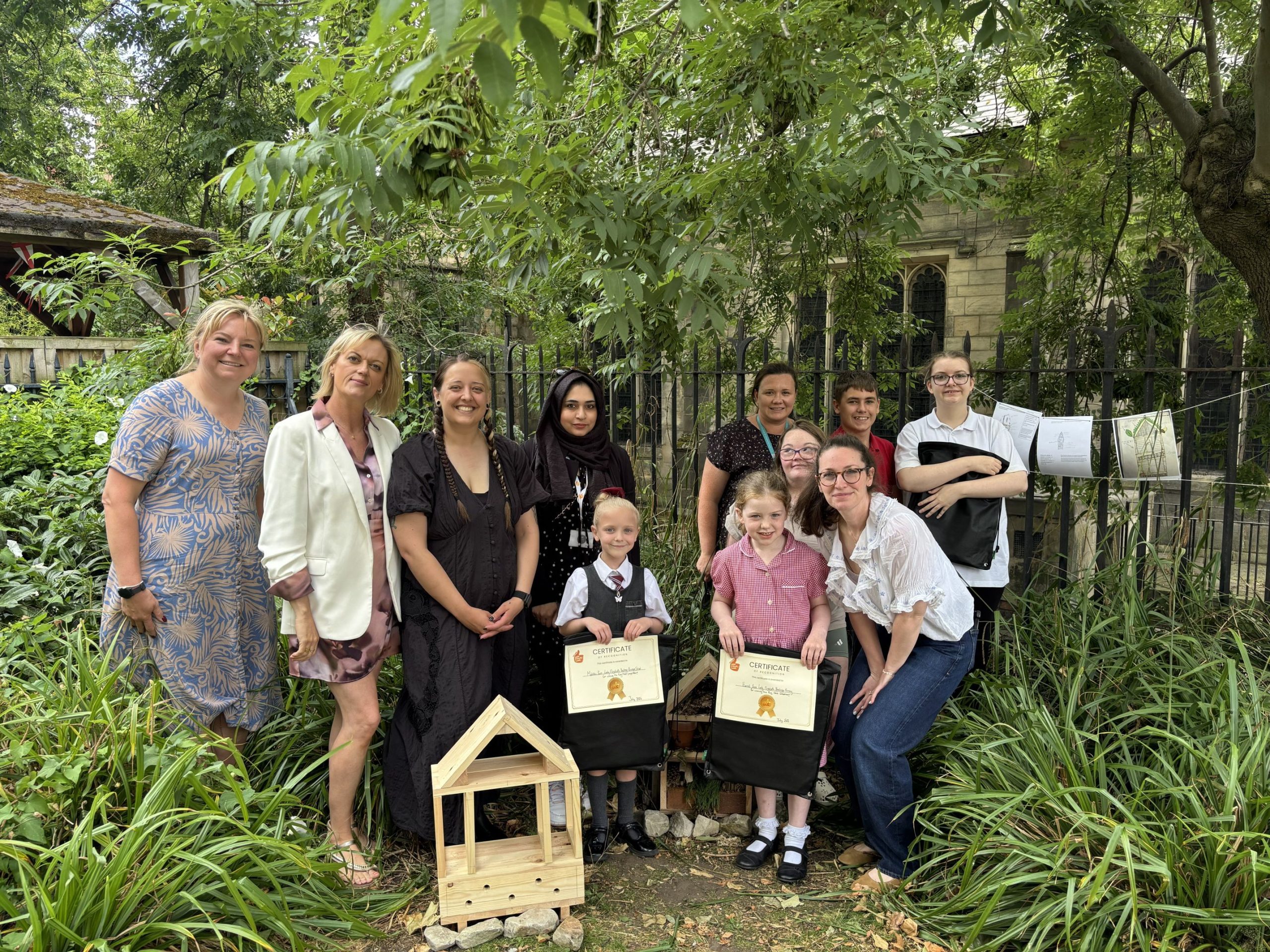 a group of people and children in a garden stood around looking at the camera