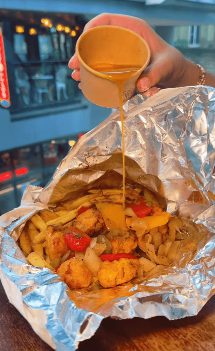 a person pouring a sauce onto a plate of food