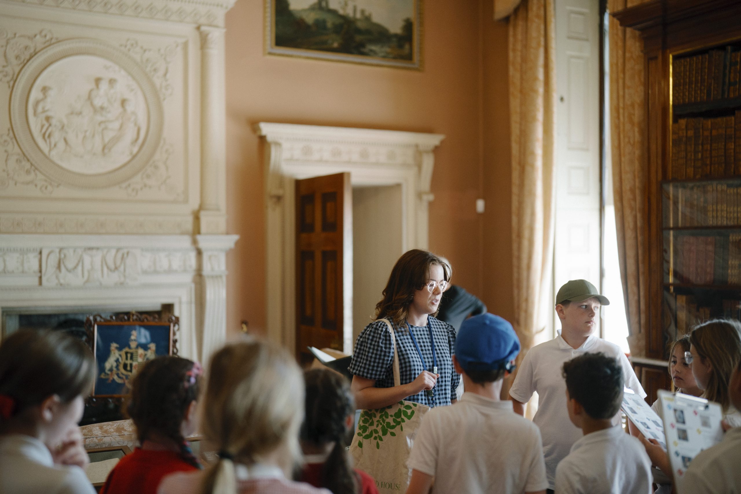 the interior of a high ceiling room with ornate decorations a group of children and an adult speaking to them