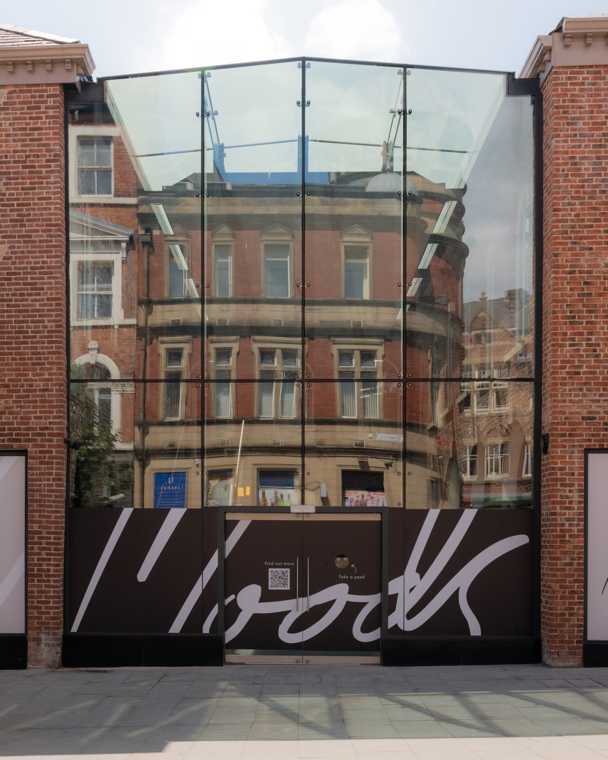 the front of a building thats glass panels between red brick