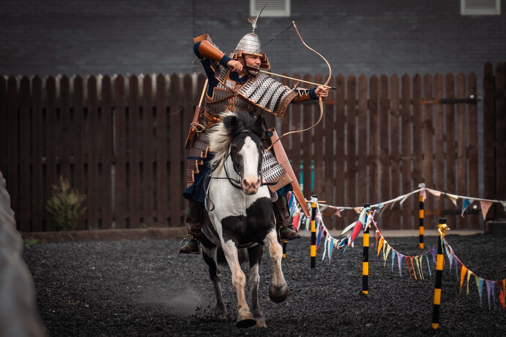 a man on horseback in armour and using a bow and arrow